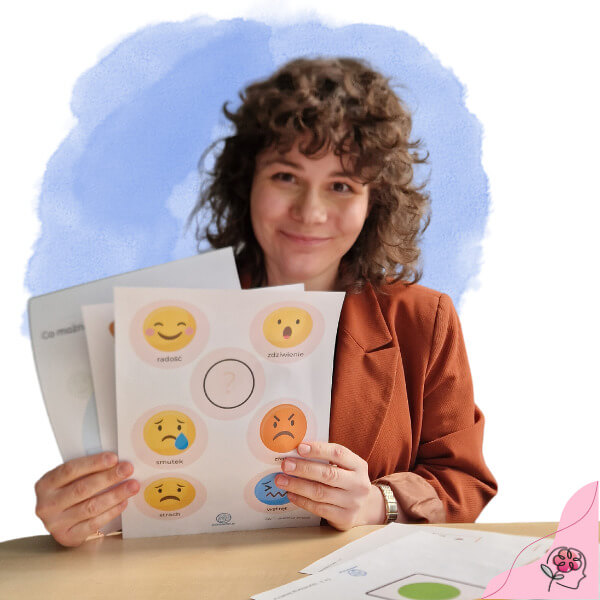 Pani Katarzyna Byrska, psycholog dziecięcy i logopeda, trzymająca w rękach kartki z testami dla dzieci za stołem